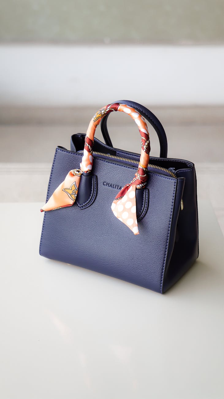 Woman smiling, holding a stylish designer handbag.